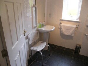 Bathroom features a sink, mirror, and window, with a towel rack and trash bin.