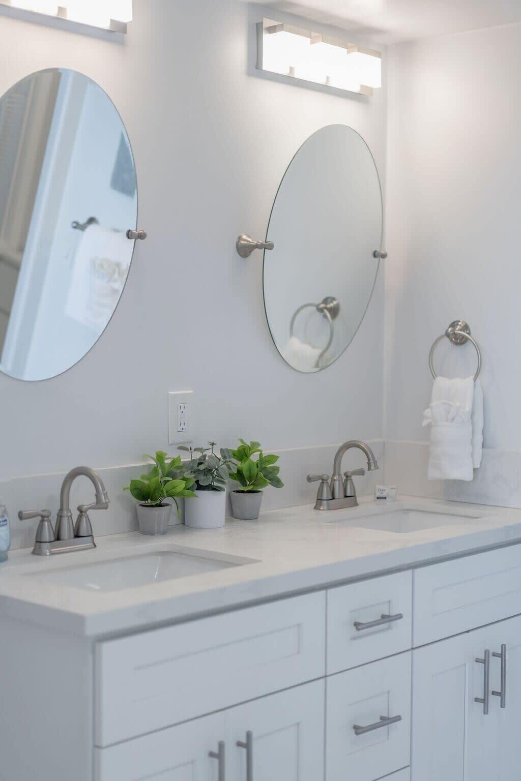 A modern bathroom with two sinks, a large mirror, and a towel rack.