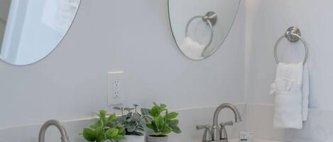 A modern bathroom with two sinks, a large mirror, and a towel rack.
