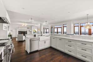 A spacious kitchen with white cabinetry, a large island, and a view of the city through large windows.