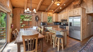 A wooden cabin with a kitchen featuring a central island, bar stools, and a dining table. - Sweet Tahoe Cabin, Lake Views/Hot Tub/Secluded (Carnelian Bay)