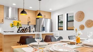 A modern kitchen with wooden cabinets, stainless steel appliances, and a dining area set for a meal.