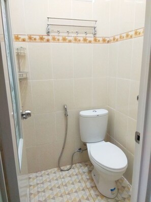 A small bathroom with a toilet, a shower, and a glass door. - Pesona Mentari Homestay by FH Stay (Ngaglik)