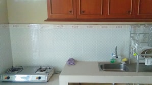A kitchen with a gas stove, a sink, and wooden cabinets. - Pesona Mentari Homestay by FH Stay (Ngaglik)