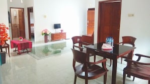 A dining area with a table and chairs, a wooden cabinet, and a TV on the wall. - Pesona Mentari Homestay by FH Stay (Ngaglik)
