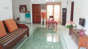 A spacious living room with a sofa, a dining table, and a TV. - Pesona Mentari Homestay by FH Stay (Ngaglik)