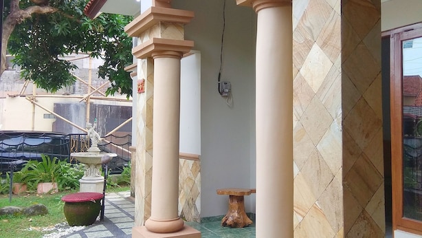 A covered outdoor area with a tiled floor, columns, and a fountain. - Pesona Mentari Homestay by FH Stay (Ngaglik)