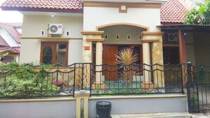 A two-story building with a tiled roof, a gated entrance, and a small garden area with plants. - Pesona Mentari Homestay by FH Stay (Ngaglik)