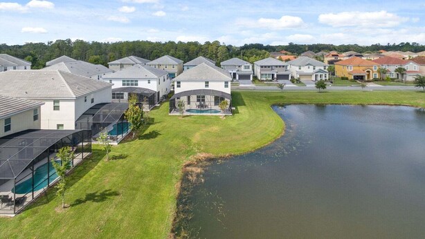 A residential area with houses, a swimming pool, and a pond. - Spacious 10BR resort home with private pool, game room, and room for 25. (Kissimmee)