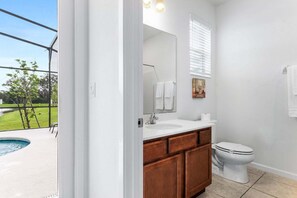 Un baño con un ventanal grande, un lavabo, un inodoro y una pequeña piscina visible desde el exterior.