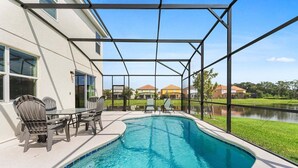 A swimming pool with a covered patio area, outdoor seating, and a view of a residential neighborhood. - Spacious 10BR resort home with private pool, game room, and room for 25. (Kissimmee)