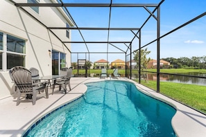 A swimming pool with a covered patio area, outdoor seating, and a view of a residential neighborhood. - Spacious 10BR resort home with private pool, game room, and room for 25. (Kissimmee)