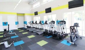 Un gimnasio con cintas de correr, elípticas y máquinas de pesas.