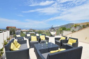 An outdoor seating area with wicker furniture and yellow cushions, overlooking a scenic landscape. - Lovely 3-bed House in Sorrento for Families (Sant'Agnello)