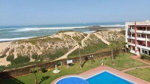 Un hotel con piscina, vistas a la playa y un edificio de varios pisos.