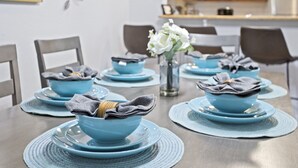 Una mesa puesta con cuencos y platos azules, sobre un mantel tejido.