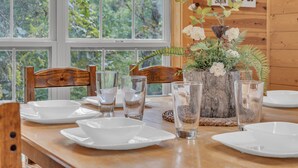 Una mesa de comedor dispuesta con platos y vasos blancos, una silla de madera y un letrero que dice 