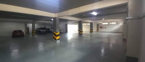 An indoor parking garage with concrete pillars and striped safety markings.