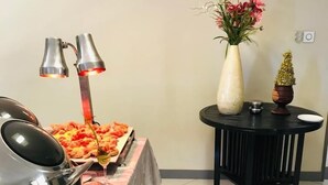 Un tavolo da buffet con cibo, un vaso con fiori e un piccolo tavolo con una candela.