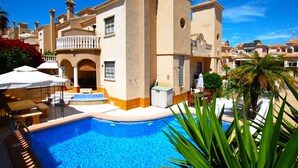 Un área de piscina con una piscina azul cristalina, sillas de descanso y sombrillas.