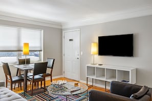 A modern living room with a dining table, chairs, a sofa, a TV, and a door. - B1bk Professional Condo w Wi-fi Perfect for Business Travelers (Atlanta)
