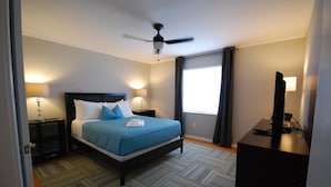 A neatly arranged hotel room with a bed, bedside lamps, a desk with a computer, and a ceiling fan. - B1bb Enjoy a Full Kitchen in an Affordable Condo Near Peachtree Street (Atlanta)