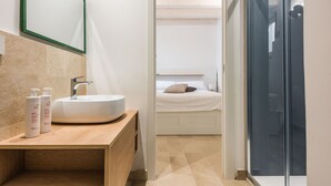 Ein modernes Badezimmer mit einem Holzwaschtisch, einem weißen Waschbecken und zwei Shampoo-Flaschen.
