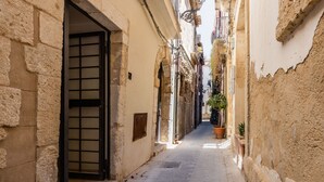 A narrow alleyway with stone walls and a door with a grid pattern. - Giudecca's Studio with Terrace by Wonderful Italy (Siracusa)