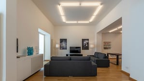 Una sala de estar moderna con un sofá seccional, un televisor de pantalla plana y un comedor con una mesa y sillas.