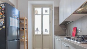 Una cucina moderna con frigorifero nero, una finestra a doppia anta e piano cottura a gas.