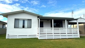 Uma casa móvel térrea com varanda coberta e um pequeno deck.