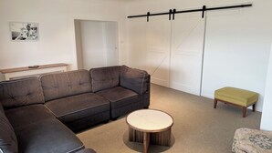 Uma sala de estar moderna com sofá modular, mesa de centro redonda e um pequeno banquinho.