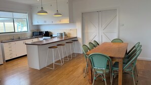 Cozinha moderna com uma ilha central, banquetas de bar e uma mesa de jantar com cadeiras.