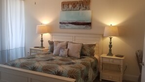 Een slaapkamer met een bed, twee nachtkastjes, een wandlamp en een schilderij.