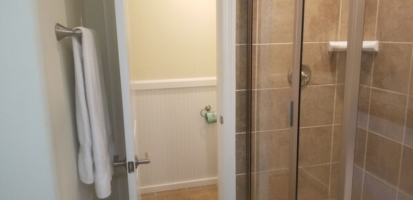 A bathroom with a glass shower door, a towel rack, and a toilet paper holder.