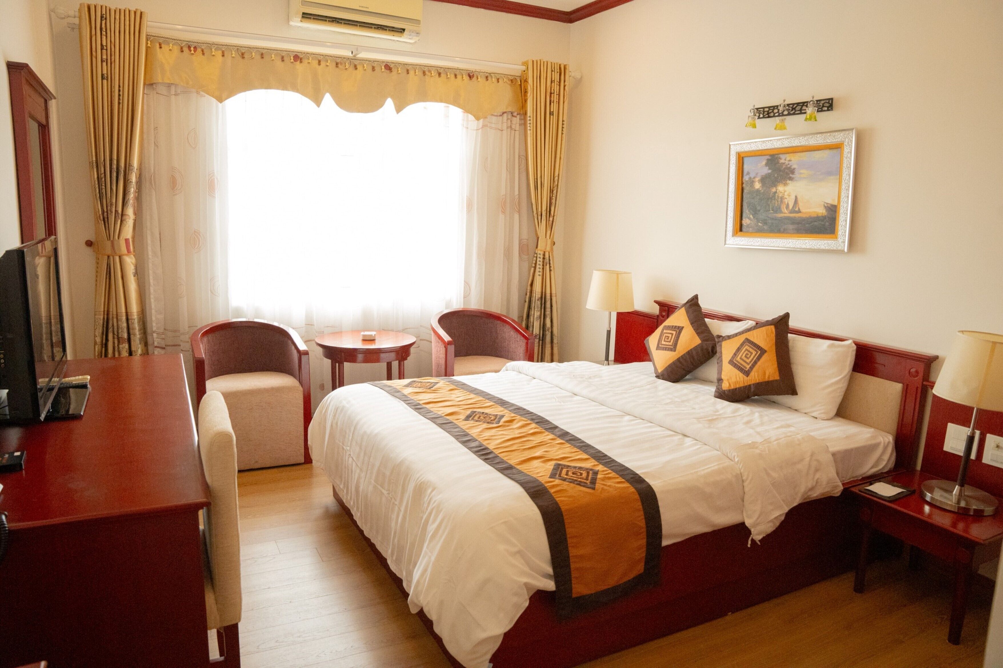 Una habitación de hotel con una cama grande, un escritorio, una silla y una mesita.