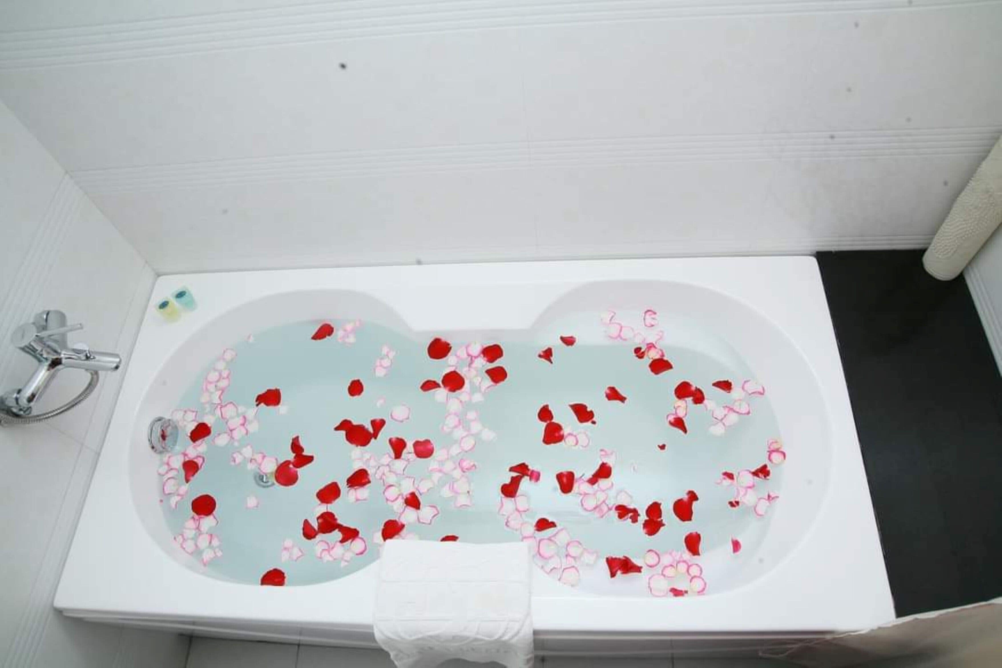 A bathtub filled with water and rose petals.