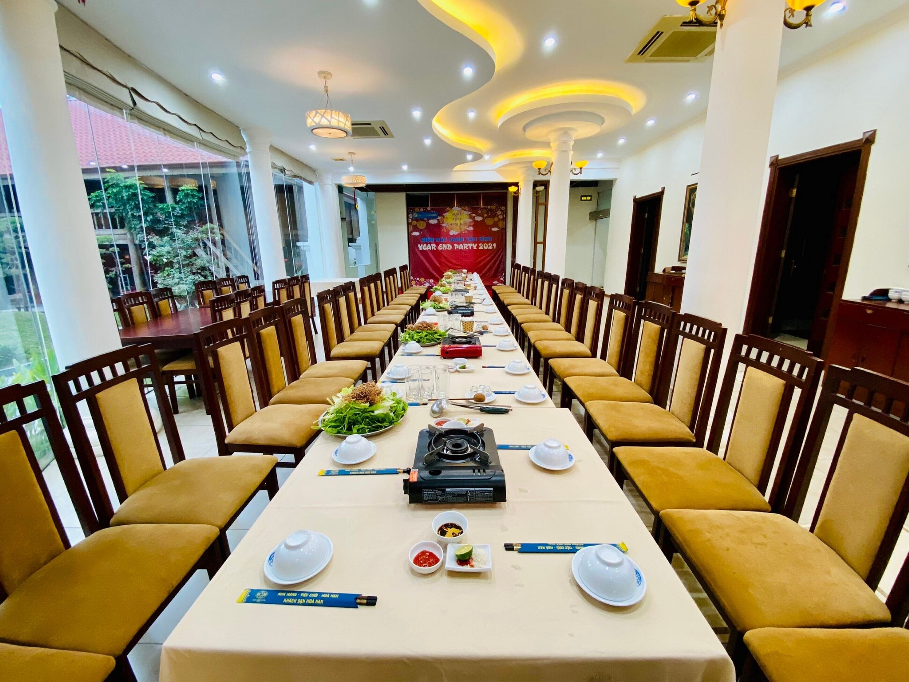 A long banquet table set for a formal event, with chairs on both sides and a banner in the background.