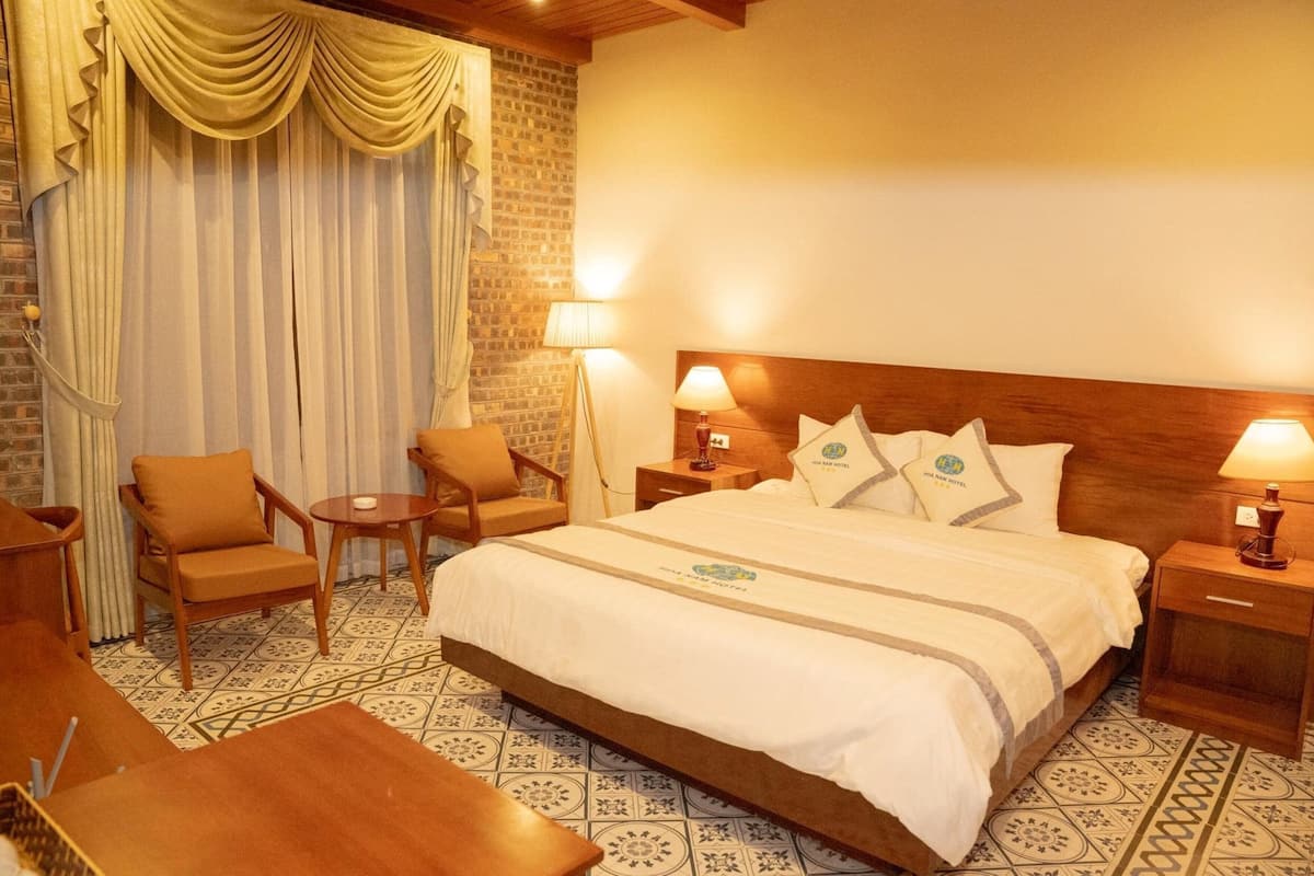 A hotel room with a large bed, two bedside tables with lamps, a chair, and a small table.