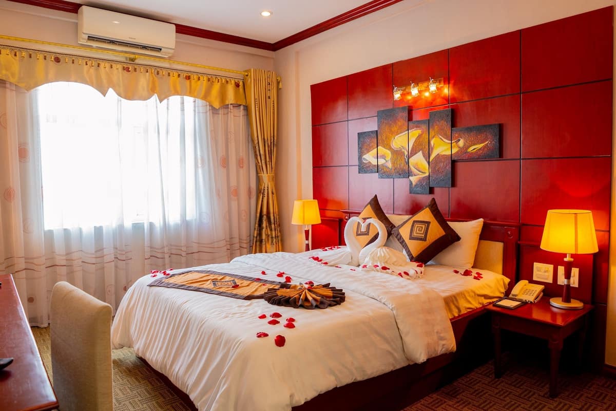 A hotel room with a large bed, two bedside lamps, a desk, and a chair.