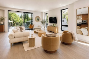 Un salon moderne avec un canapé, des fauteuils, une table basse et un téléviseur.