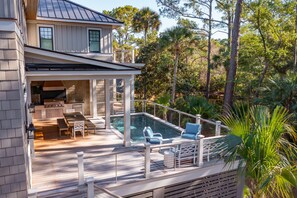 Et hus med terrasse, udendørs køkken og swimmingpool.