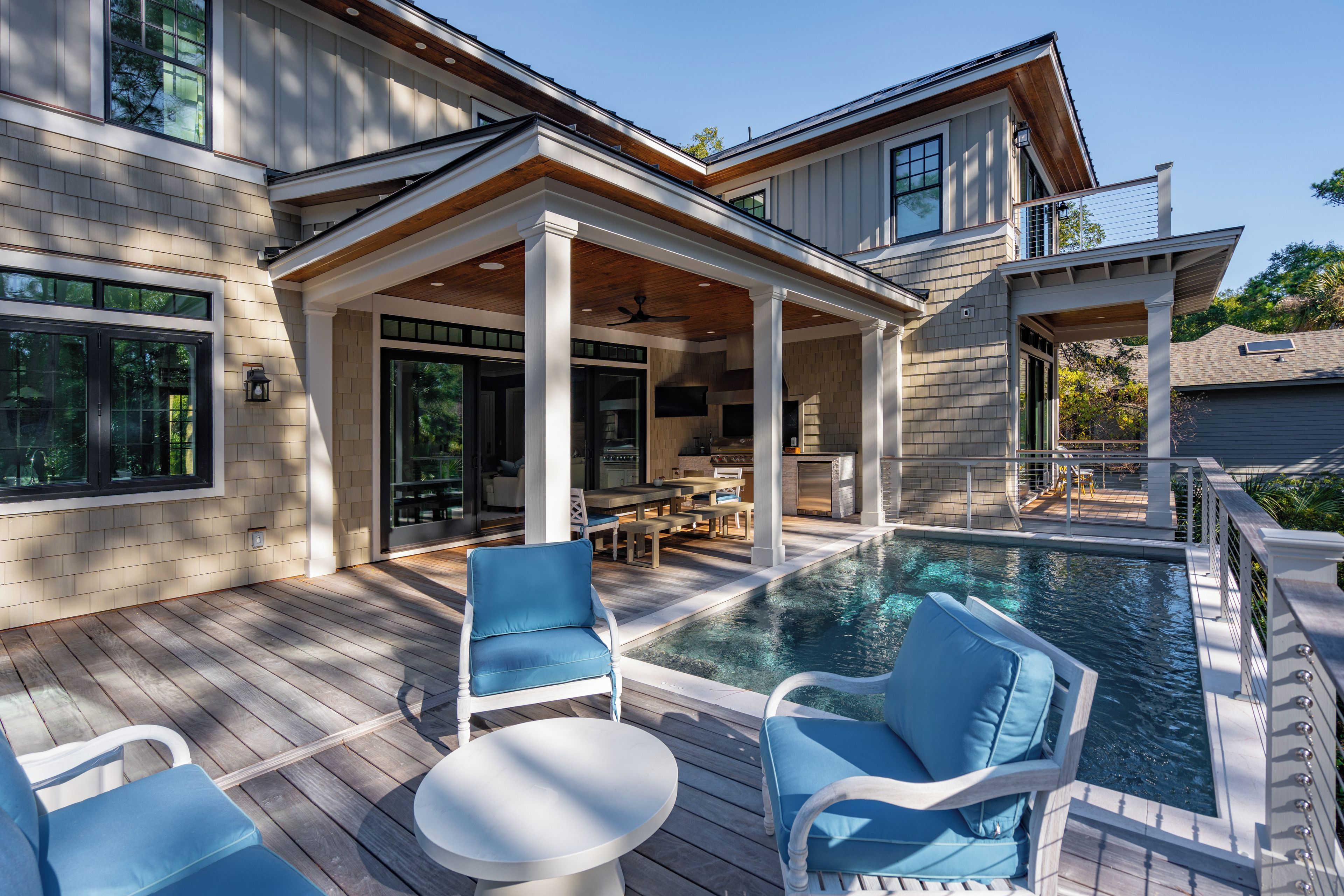 A modern house with a pool, outdoor furniture, and a covered patio area.