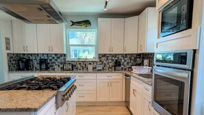 A modern kitchen with white cabinets, a granite countertop, a stainless steel range, a microwave, and an oven. - St.George Island Bayfront Paradise with Pool,Dock (St. Geroge Island)