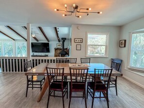 A dining area with a large table and chairs, a fireplace, and a television.