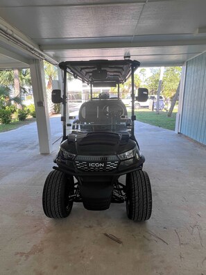 A golf cart parked inside a covered area with a concrete floor. - St.George Island Bayfront Paradise with Pool,Dock Golf Cart Included (St. Geroge Island)