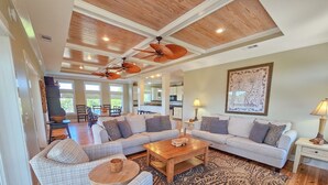 A spacious living room with a high ceiling, a large sofa set, a coffee table, and a patterned rug. - Private Screened Pool, Easy Beach Access in Plantation! (St. George Island)