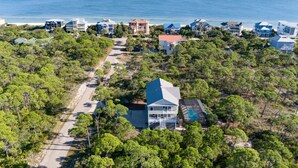An aerial view of a coastal residential area with multiple houses, a road, and a beach in the background. - Private Screened Pool, Easy Beach Access in Plantation! (St. George Island)