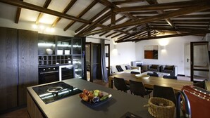 Una cocina moderna con una isla central, electrodomésticos integrados y un comedor con una mesa grande y sillas.