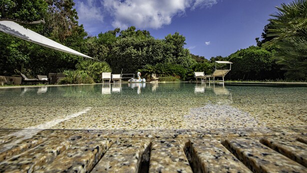 Una piscina cristalina con sillas de descanso y un flotador decorativo de flamenco.